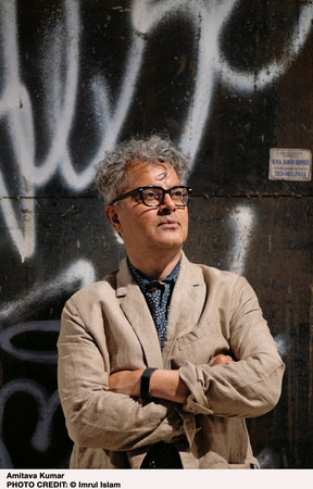 A portrait of the author standing in front of a graffiti'd wall 