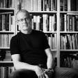 Don Gillmor poses sitting in front of a bookshelf.