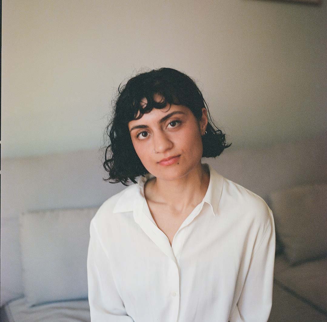 The author Bahar Orang, in a white button-down shirt, seated on a grey couch 