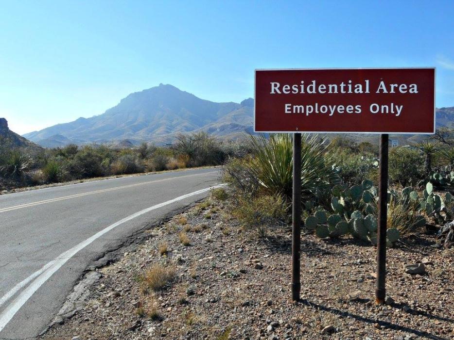 An employees-only sign beside a road in Big Ben National Park. There are mountains in the background. 