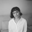 The author Bahar Orang, in a white button-down shirt, seated on a grey couch 